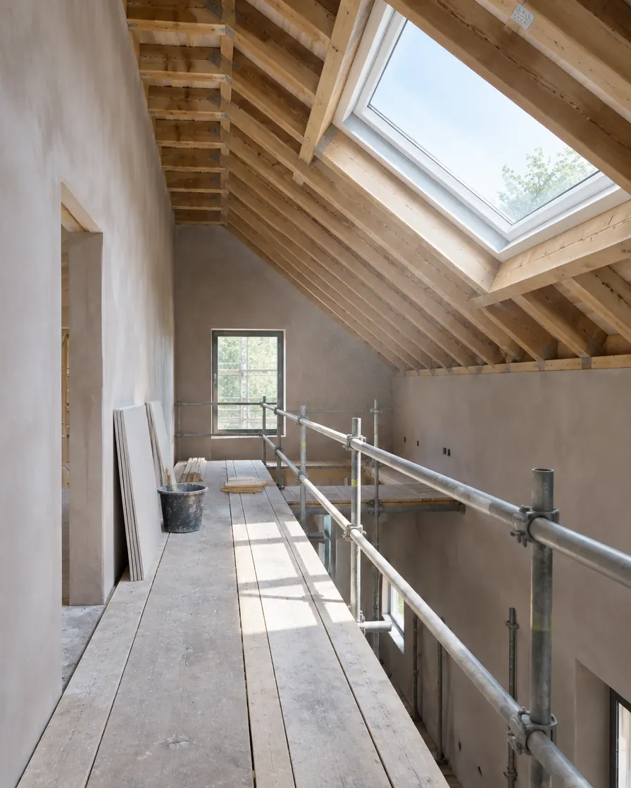 Renovation in progress with exposed timber joists and fresh plaster